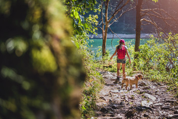 Girl with a dog hiking by the lake