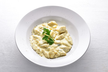 Dumpling from potatoes under cheese sauce. On a wooden background. Top view. Free space.