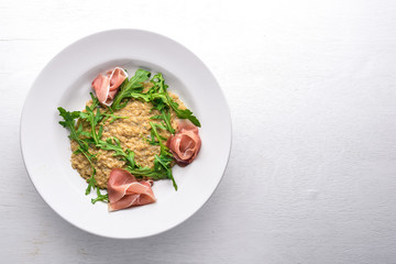 Risotto with diced meat and arugula. Top view. Free space.