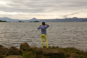 Fototapeta na wymiar woman standing on rock looking at the lake toba