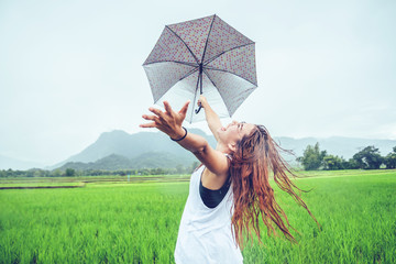 Asian women travel relax in the holiday. Women stand in rain umbrellas. On the meadow During the...