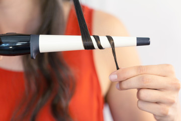 Naklejka premium Hairstylist curling hair client in hairdressing salon