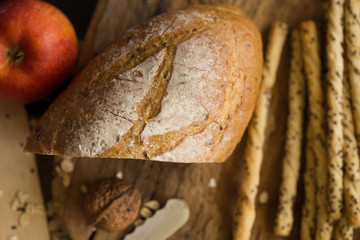 French bread baguette cut on wooden board with knife. with a chocolate butter and red apple.