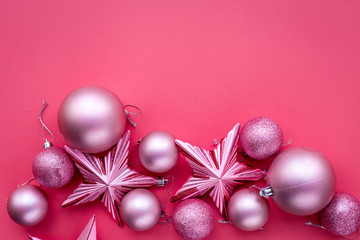 Christmas toys concept. Pink balls and stars on pink background top view copyspace