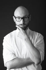 young white beard wearing glasses man white shirt black pants studio monochrome background