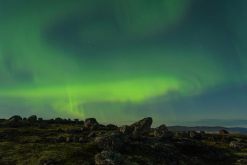 The Aurora in the sky above the hills at night .