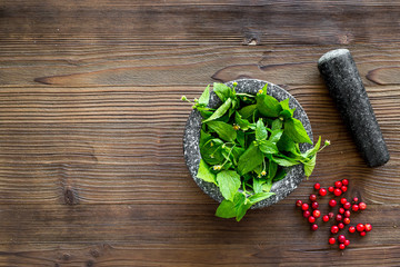 Food set with various herbs and berries for making spices and mortar wooden background top view mockup