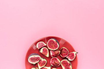 Fresh blue figs sliceson plate on pink background top view copyspace