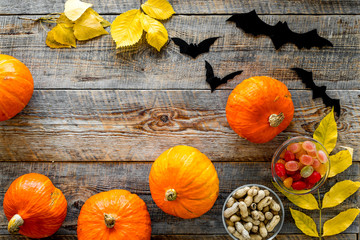 Halloween background. Pumpkins, paper bats and autumn leaves on wooden background top view copyspace