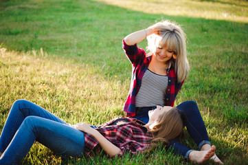 Two happy female friends playing and having fun in green grass