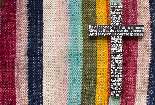 Wooden cross with the Lord's prayer on the  colored carpet background.