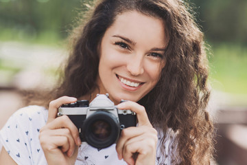 Young beautiful woman taking photographs with retro styled digital photo camera