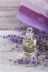 Obraz na płótnie Canvas Bottle of essential oil and fresh lavender flowers on a white wooden background. Aromatherapy, spa and wellness concept