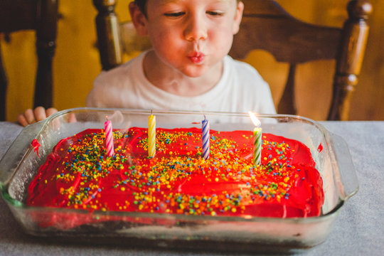Young boy blowing out candles on his birthday cake