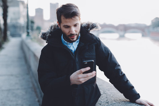 Man holding mobile phone during a cold evening