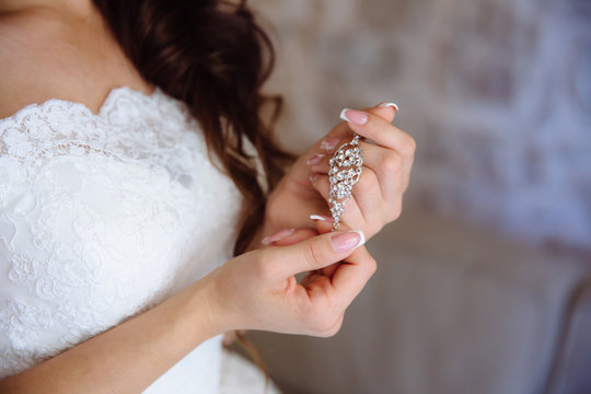 Earrind in the hands of the bride. Concept of jewelry