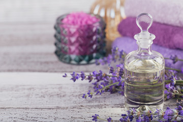 Obraz na płótnie Canvas Bottle of essential oil and fresh lavender flowers on a white wooden background. Aromatherapy, spa and wellness concept