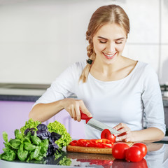 A young woman is preparing food in the kitchen. Copy space. The concept is healthy food, diet, vegetarianism, weight loss.