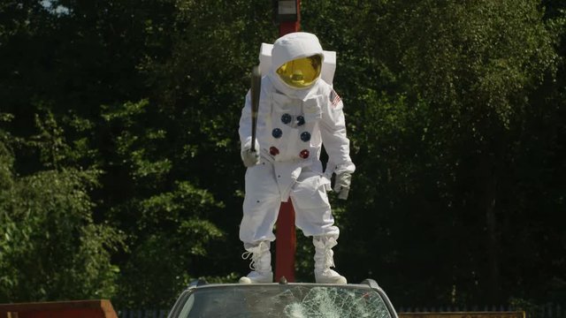  Hooligan astronaut smashing car windshield with a baseball bat.