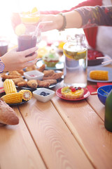 Top view of group of people having dinner together while sitting at wooden table. Food on the table. People eat fast food.