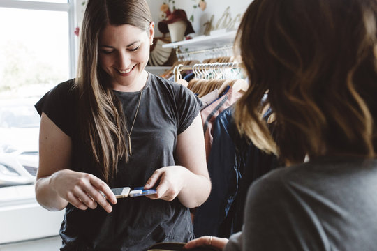Woman using phone to pay in boutique