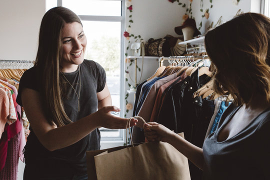 Clothing store owner helping customer with purchase