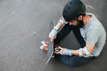 Professional skater checks his skateboard after training. Extreme sport challenge and competition, skateboarder safety equipment and urban lifestyle of young people background with free space © golubovy