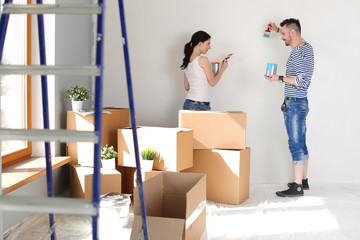 Portrait of happy smiling young couple painting interior wall of new house. young couple