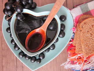 in a bowl,on a wooden floor hearted, molasses, a wooden spoon and bread slices on the side. healthy fruits. 