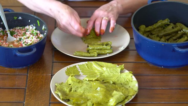 Turkish woman making Sarma - Traditional Turkish food. Grape leaves stuffed with rice and minced meat.