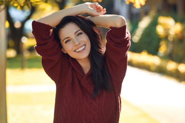 Portrait of beautiful brunette woman in autumn red sweater. Cute girl walks in the autumn park