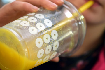 Close up of young woman drinking a yellow mango smoothie. Selective focus.