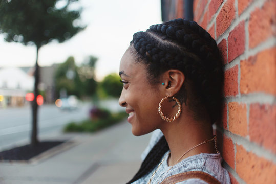 A young african american woman leaning against a brick wall