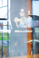 Obraz premium Young woman sitting at office table with laptop,view through window. Young woman