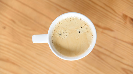 Weiße Kaffeetasse mit Kaffee auf Holzuntergrund mit diagonalem Muster- Flat Lay