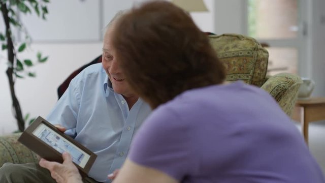 Cheerful senior man and woman looking at a picture and chatting in nursing home.