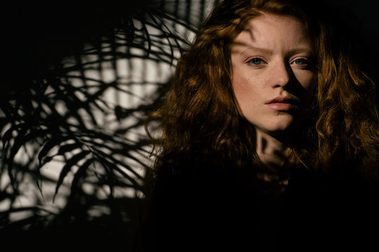 Beautiful ginger girl portrait with palm tree shadow on her face