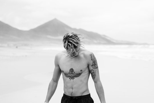 Portrait of man on the beach shanking his hair