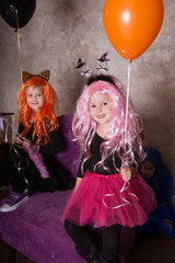 Halloween girls  Costumes of Witches looking at camera with balloons on holiday
