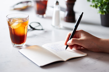 Close-up of person writing to do list with coffee on table