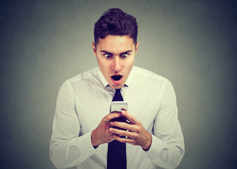 surprised man looking at phone seeing unexpected news or photos with wonder emotion on face