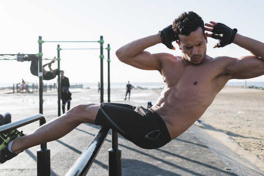 Young man doing abdominal exercises outdoors