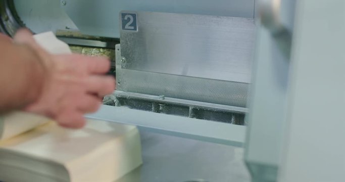 Preparing Book and Placing Into the Glue Cover Binding Machine Close Up. a worker flips through pages in a book to separate and places the pages into a machine for binding the cover 
