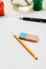 Pencil and eraser on a blank sheet of paper, vertical