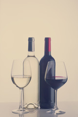 High glasses with red and white wine and two wine bottles, retro toned