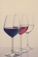 Row of three wine glasses with red, white and rose wine, retro toned