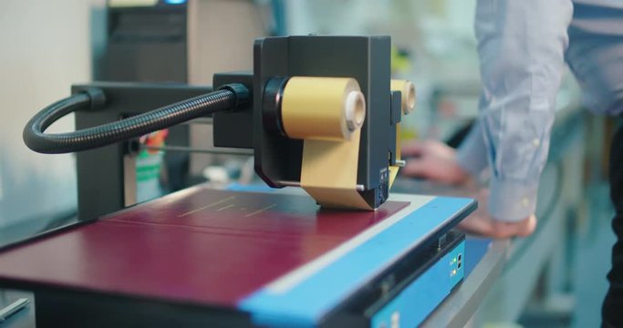 Employee Running Book Embossing Machine on Hardcover. a view moves from left to right as an employee runs a hardcover embossing machine
