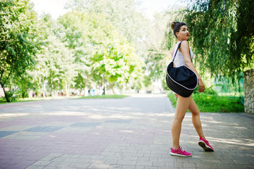 Sport girl wear on white shorts ans shirt with sport bag walking at park.