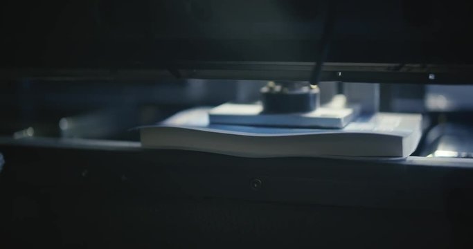 Automated Book Trimmer Machine Spins and Cuts Book from Front. a close up above view of a machine spinning a paperback book to be trimmed on all sides
