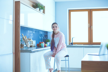 Young woman sitting on table in the kitchen.